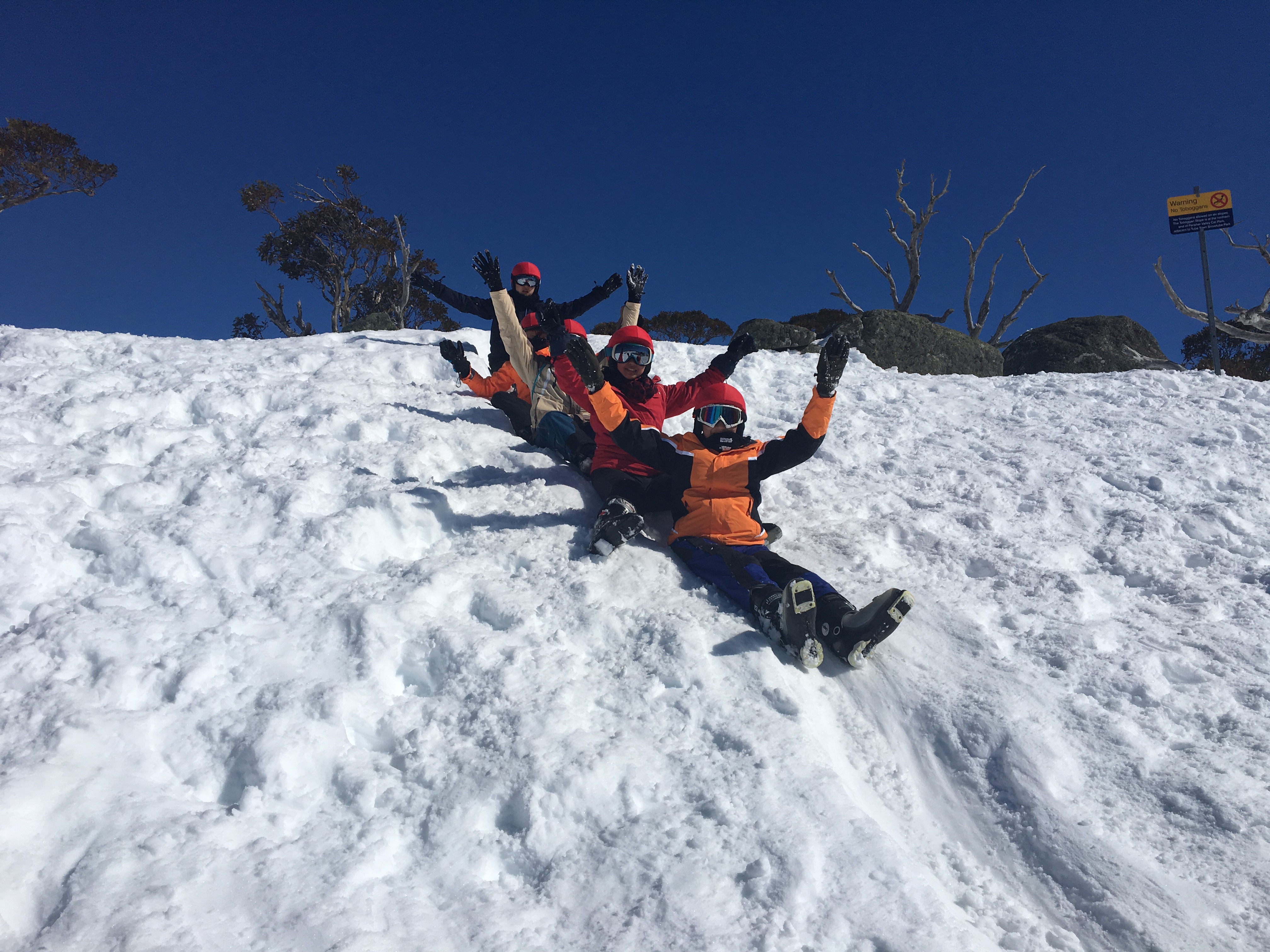 Students sliding down snowy slope